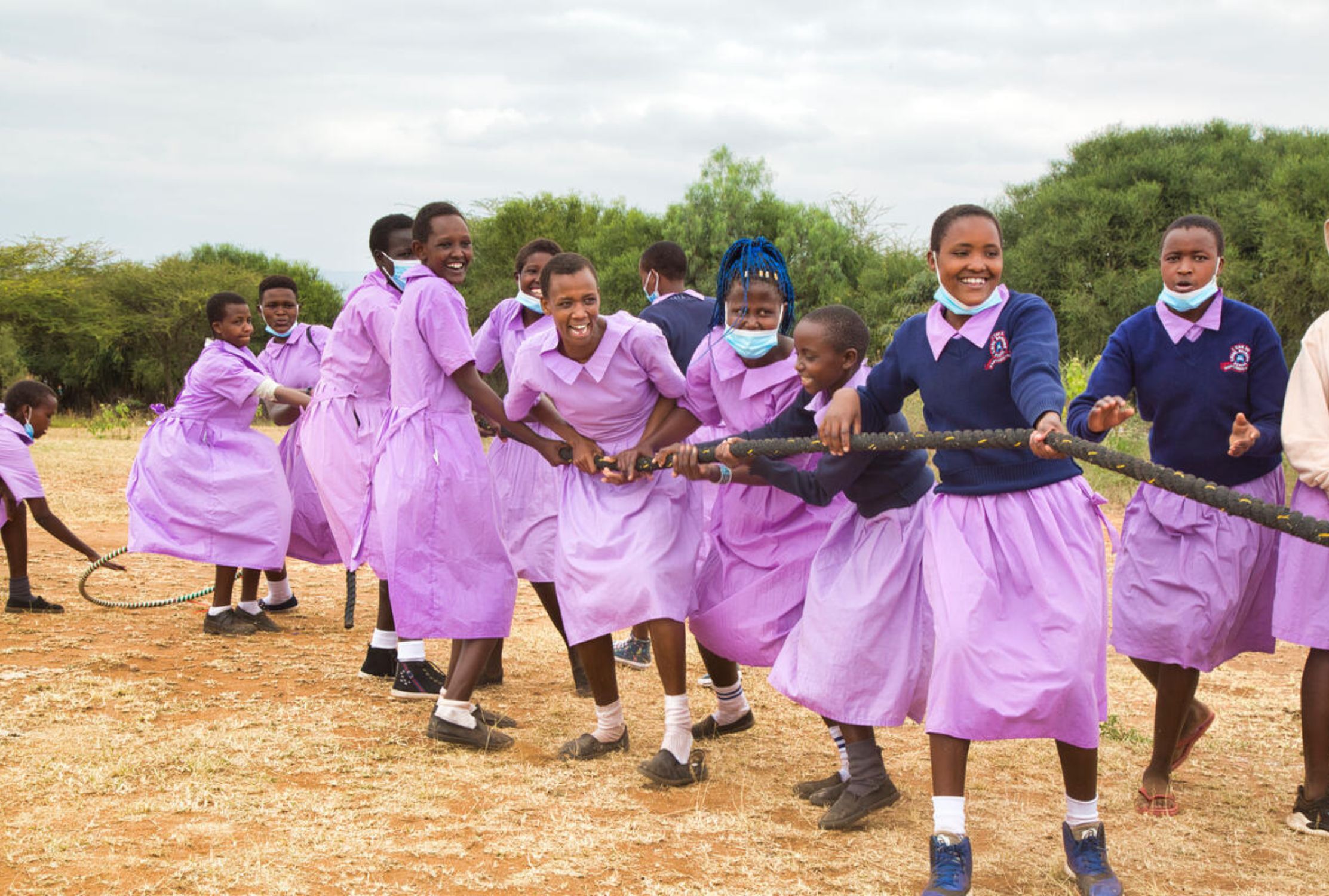 Kenyan school girls smiling and playing tug of war