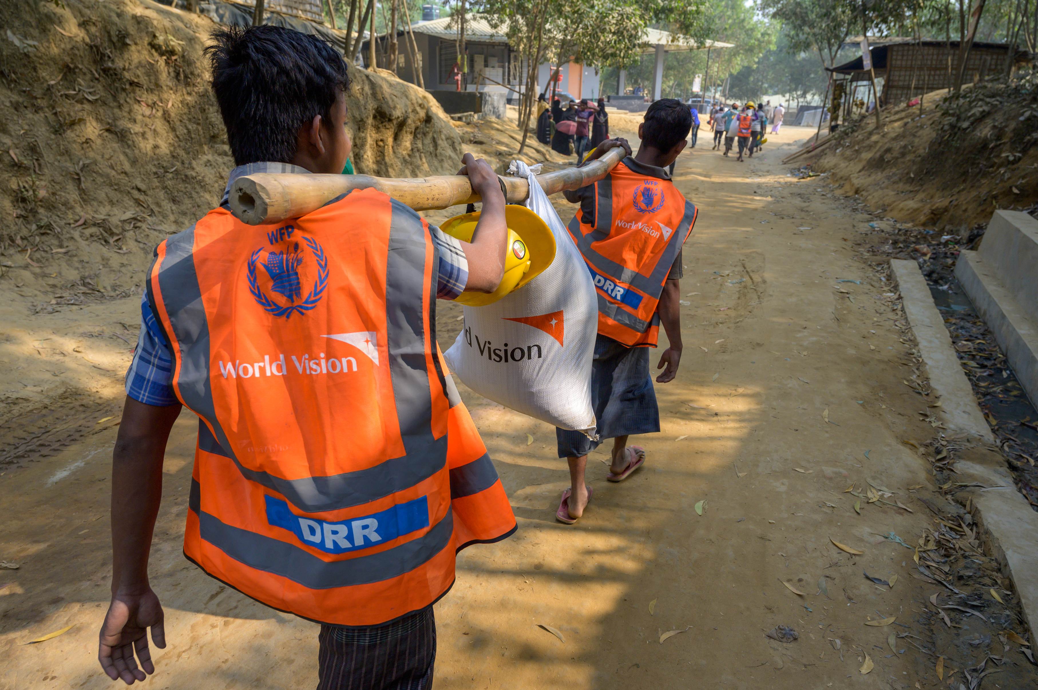 People in World Vision tops carry large pieces of wood in Bangladesh to help with a project